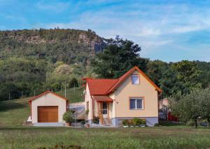 a house in a field with a mountain in the background at Bazaltorgona Apartman in Kisapáti