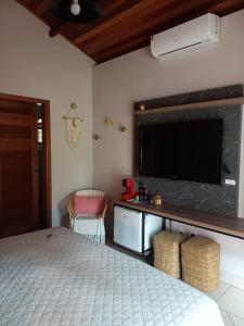 a bedroom with a bed and a flat screen tv at Casa Jabuticaba Refúgio e Hospedagem in São Miguel Arcanjo