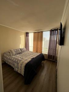 a bedroom with a bed and a television in it at Reñaca departamento in Viña del Mar