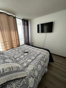 a bedroom with a bed and a flat screen tv at Reñaca departamento in Viña del Mar