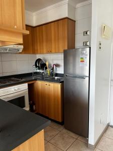 een keuken met een roestvrijstalen koelkast en houten kasten bij Reñaca departamento in Viña del Mar