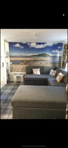 una sala de estar con sofá y una pintura de una playa en Lamlash (holiday) Lets en Lamlash