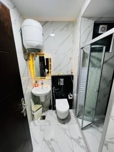 a bathroom with a toilet and a sink and a shower at شقة مفروشة بغرفتي نوم الجاردنز in Umm Uthainah