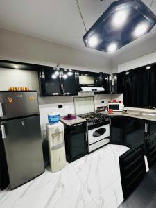 una cocina con armarios negros y electrodomésticos blancos en شقة مفروشة بغرفتي نوم الجاردنز en Umm Uthainah