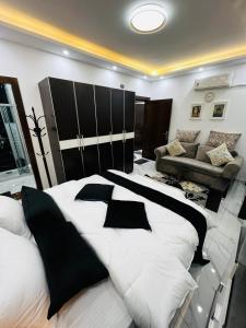 a large white bed with black pillows in a room at شقة مفروشة بغرفتي نوم الجاردنز in Umm Uthainah