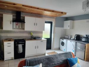 Self Catering apartment Achill Island Pets Allowed في ويستبورت: مطبخ فيه دواليب بيضاء و كنب