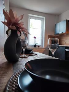 une table avec un vase noir et deux verres à vin dans l'établissement Ferienwohnung Mephisto und Faust, à Thale