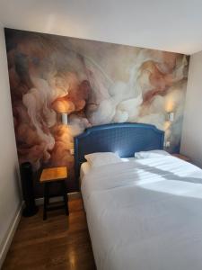 a bedroom with a bed with a painting on the wall at Le gîte du peintre in Entrains-sur-Nohain