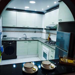 a kitchen with white cabinets and a black counter top at Moderne Appartement au plein Centre-Ville en Face Hilton in Tangier