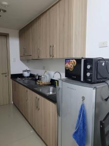 La cuisine est équipée d'un évier, d'un four micro-ondes et d'un réfrigérateur. dans l'établissement Shore residences Ph, à Manille