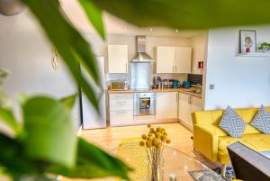 a living room with a yellow couch and a kitchen at Cute 2 bed flat in the heart of Derby By 20Property Stays Short Lets & Serviced Accommodation in Derby