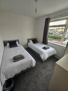 2 camas en una habitación con ventana en Stunning 5 bed with free parking, en Aldershot