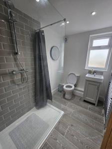 y baño con ducha, aseo y lavamanos. en Stunning 5 bed with free parking, en Aldershot