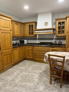 eine Küche mit Holzschränken und einem Tisch darin in der Unterkunft Casa Orbara, a 8 Km de Pamplona in Ardanaz
