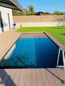 a swimming pool with a wooden deck and blue water at VOO residence in Malečnik