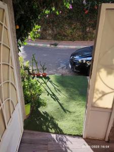 une porte ouverte menant à une allée avec une voiture garée dans l'établissement Marrakech golf city, à Marrakech