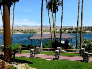 a walkway with palm trees and a view of the water at The New Pioneer in Laughlin