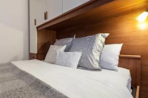a bed with white pillows and a wooden headboard at MilanRentals - Baires Apartment in Milan