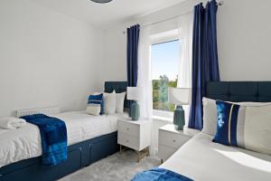 2 camas en un dormitorio con cortinas azules y ventana en New Build 3 Bed House by AV Stays Short Lets Kent With Free Parking Ideal For Contractors en Sittingbourne