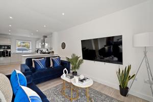 a living room with a blue couch and a table at New Build 3 Bed House by AV Stays Short Lets Kent With Free Parking Ideal For Contractors in Sittingbourne
