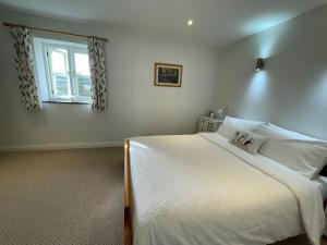 Un dormitorio con una cama blanca y una ventana. en Trefechan Wen Barn, en Llanwnda 41 fotos más