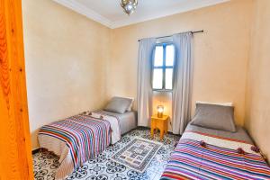 a bedroom with two beds and a window at Maison Insa in Essaouira