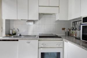 una cocina blanca con armarios blancos y fregadero en MilanRentals - Lotto Apartment, en Milán