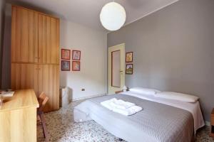 ミラノにあるMilanRentals - Lotto Apartmentの白いベッドと木製キャビネット付きのベッドルーム1室が備わります。