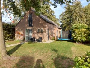 an old brick house with a playground in the yard at Rumah Senang Ewijk met royale tuin en hottub in Ewijk