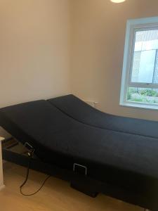 uma cama preta num quarto com uma janela em Stjernepladsen em Aalborg