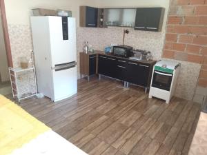 een keuken met een witte koelkast en een houten vloer bij Casa de temporada in Resende