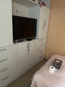 Habitación con armarios blancos, TV y cama. en Alójate en una Casa familiar, en Barranca