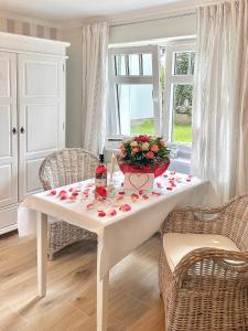 einem weißen Tisch mit Rosen und einer Vase von Blumen in der Unterkunft Villa Imme in Timmendorfer Strand