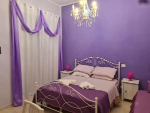 ローマにあるB&B La Casa di Gabryの紫の壁のベッドとシャンデリアが備わる紫色のベッドルーム1室が備わります。