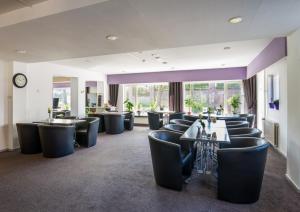 ein Restaurant mit Stühlen, Tischen und einer Uhr in der Unterkunft Hotel Eperland in Epen