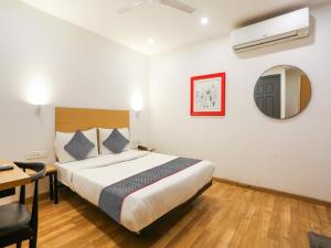 1 dormitorio con cama, escritorio y espejo en Super Townhouse 080 Meera Bagh en Nueva Delhi