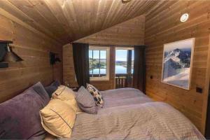 a bedroom with a bed and a large window at Exclusive Family cabin with view and beautiful Norwegian nature in Tjørhom
