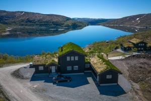 a house with grass on the roof with a body of water at Exclusive Family cabin with view and beautiful Norwegian nature in Tjørhom