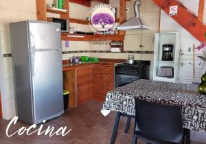 Una cocina con refrigerador y una mesa con sillas. en Cabañas Kiri, en Santa Rosa de Calamuchita