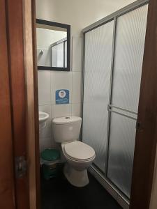 a small bathroom with a toilet and a shower at Hostal Zaguán Caldense in Manizales