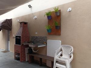 a patio with a brick oven with plants on the wall at Espaço Mar Doce Lar - Praia Indaiá e Riviera in Bertioga