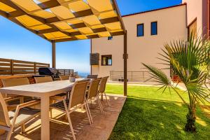 una mesa y sillas en un patio con vistas al océano en Villa Lia Chania with private ecologic pool and amazing view! en La Canea