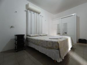 - une chambre blanche avec un lit et un miroir dans l'établissement Bom pra ficar, à Limoeiro do Norte