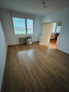 un soggiorno vuoto con pavimento in legno massello di plne vybavený 3 izbový apartmán a Stropkov