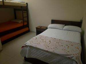 Hostal Zaguán Caldense في مانيزاليس: غرفة نوم مع سرير وسرير بطابقين