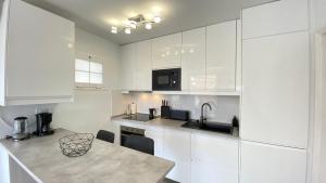 a kitchen with white cabinets and a sink and a table at Inagua Sol apartment in Puerto Rico de Gran Canaria