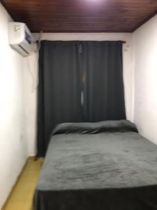 een kleine kamer met een bed met een zwart gordijn bij Alojamiento La Mamu 2 in Paso de la Patria