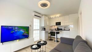 a living room with a couch and a large flat screen tv at Inagua Sol apartment in Puerto Rico de Gran Canaria