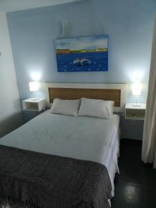 a bedroom with a large bed with two lights on it at Coco Beach Apart 3A in Natal