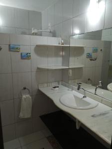 a white bathroom with a sink and a mirror at Coco Beach Apart 3A in Natal